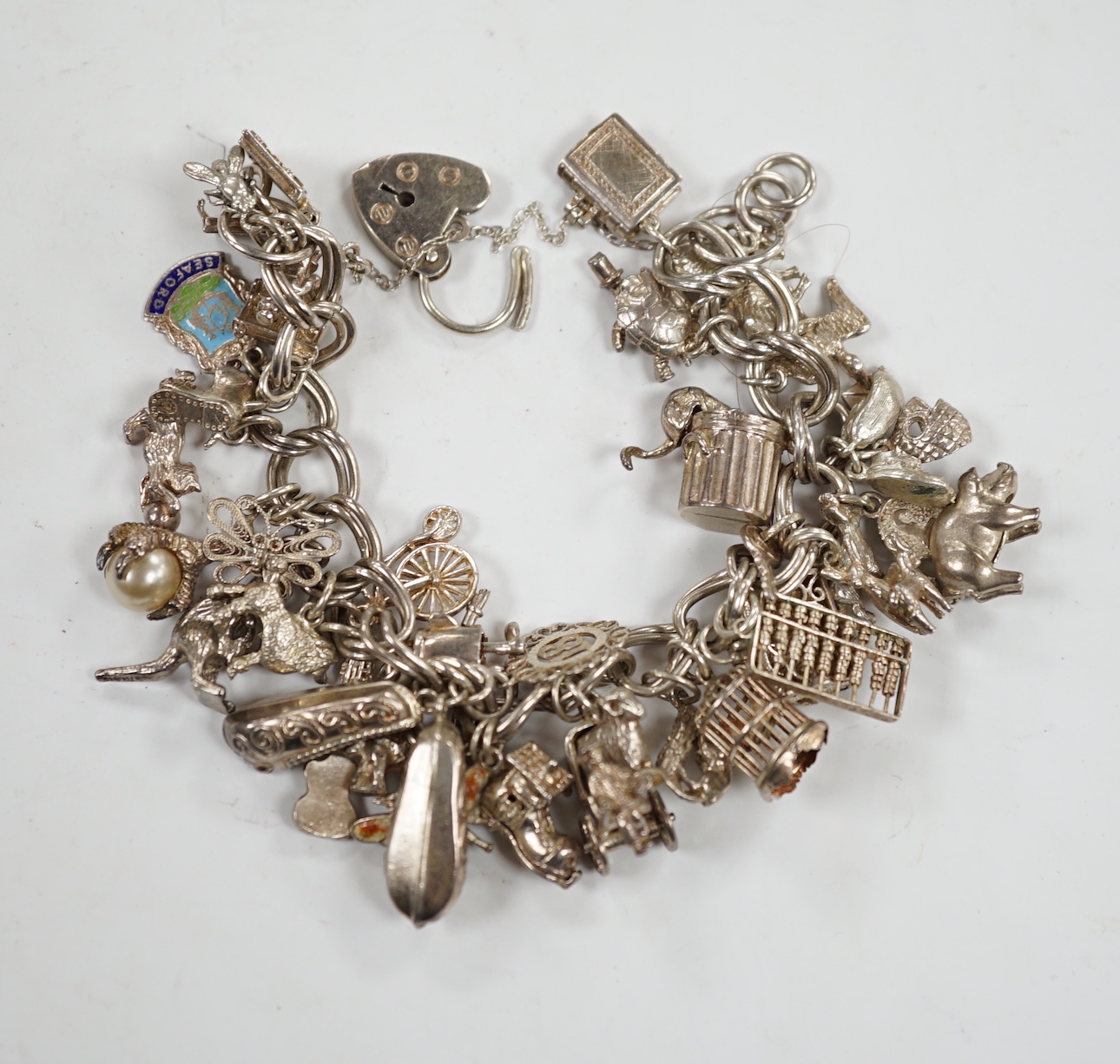 A 1970's silver charm bracelet, hung with assorted charms including birdcage, abacus, piglet, etc. and another silver charm bracelet with loose charms.
